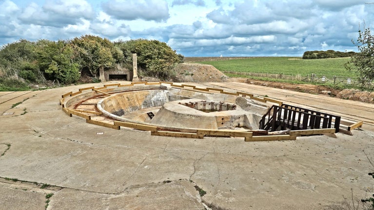 View of a semi-circular large concrete gun emplacement with scattered clouds